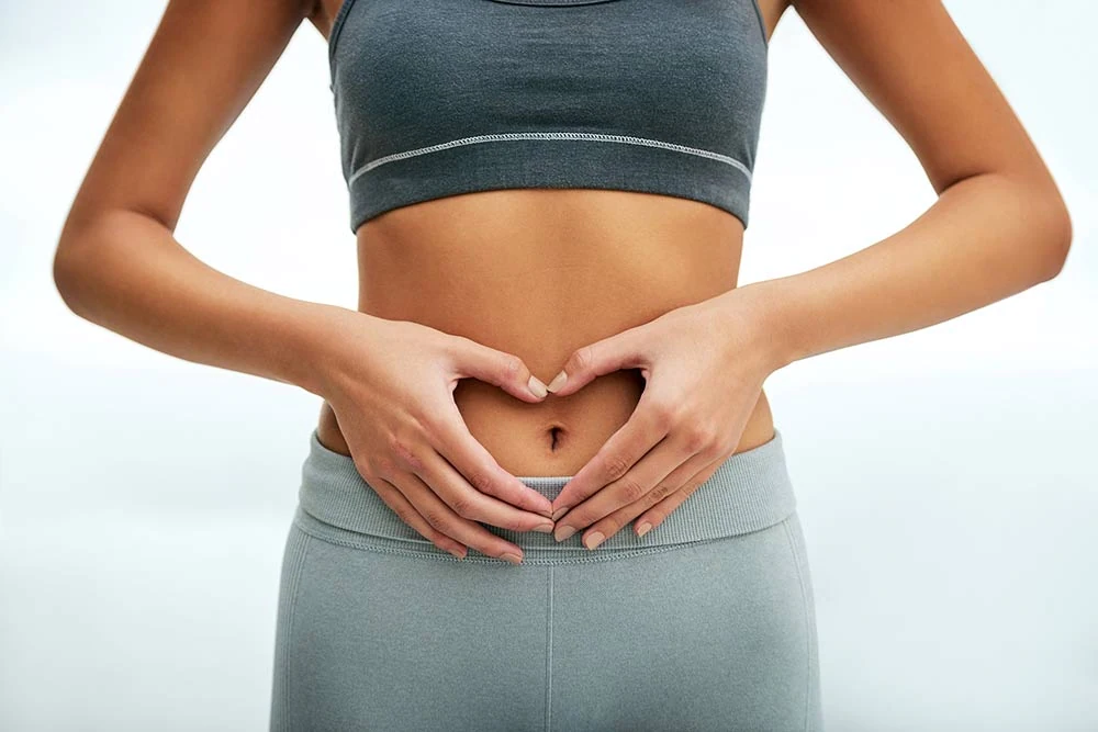 Woman making heart sign over her gut