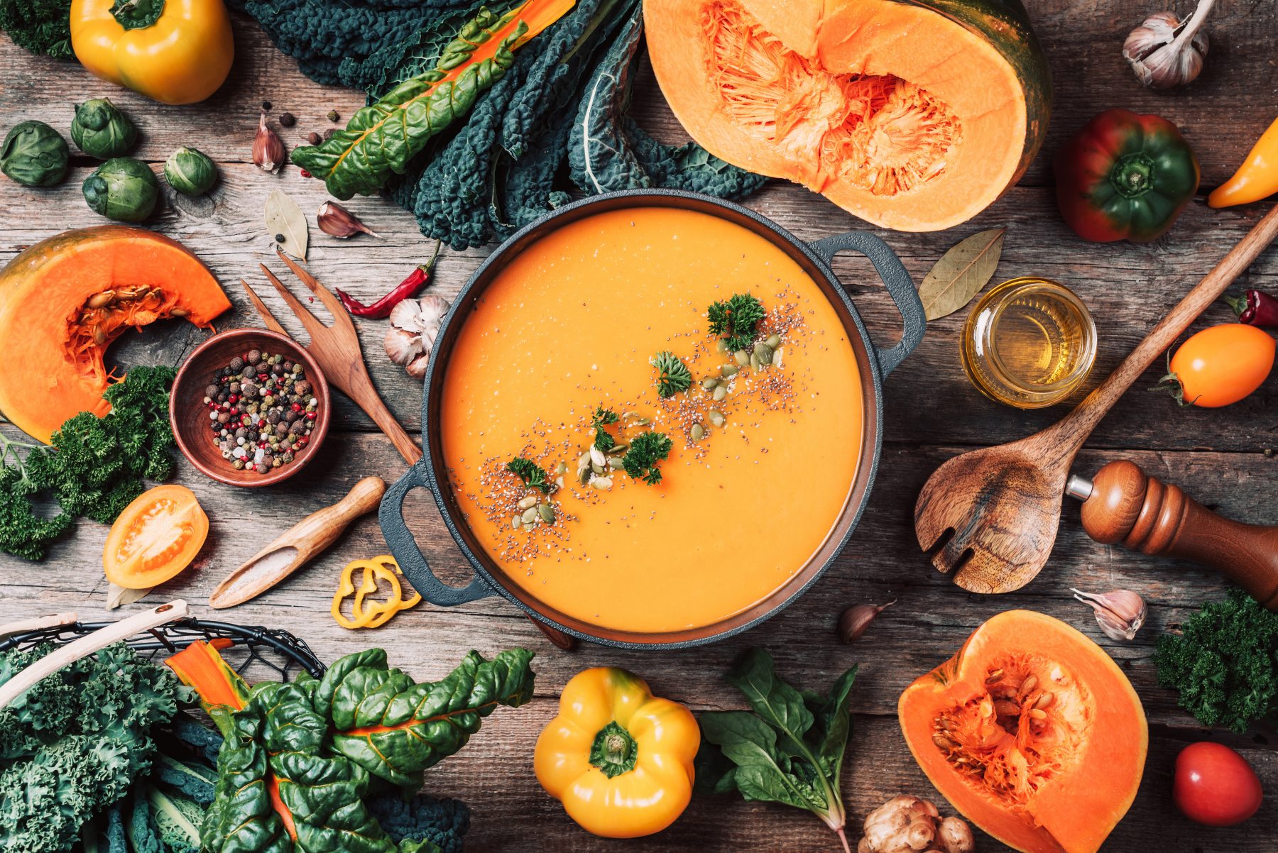 Pumpkin soup and other healthy fall foods and vegetables arranged together