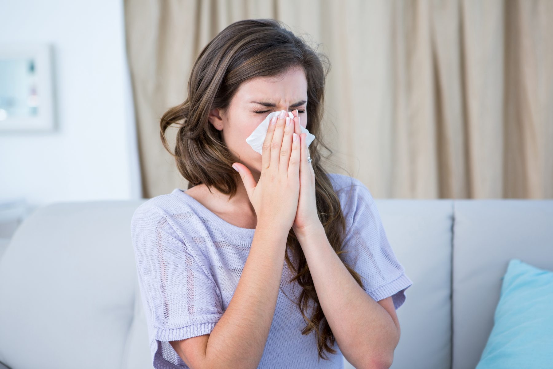 Sick woman blowing her nose because of allergies