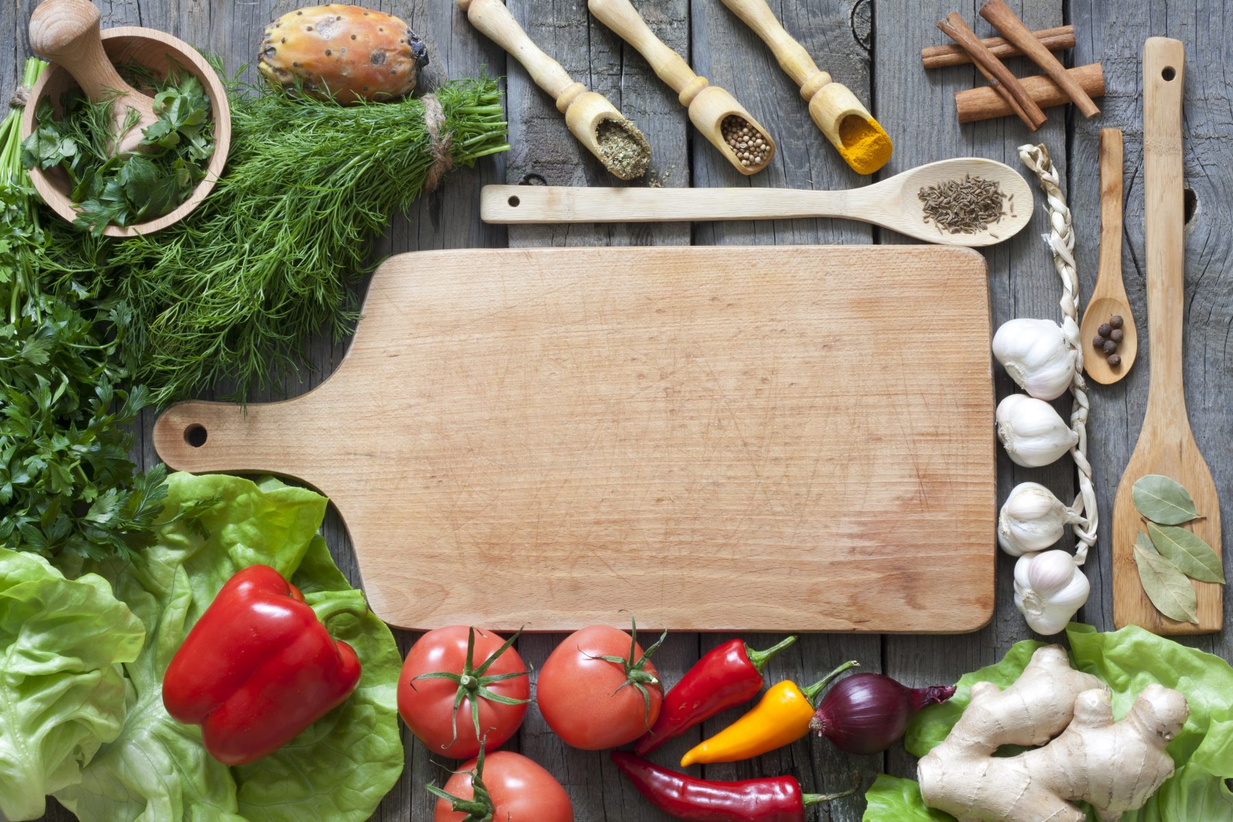 Cutting board surrounded by healthy food and herbs