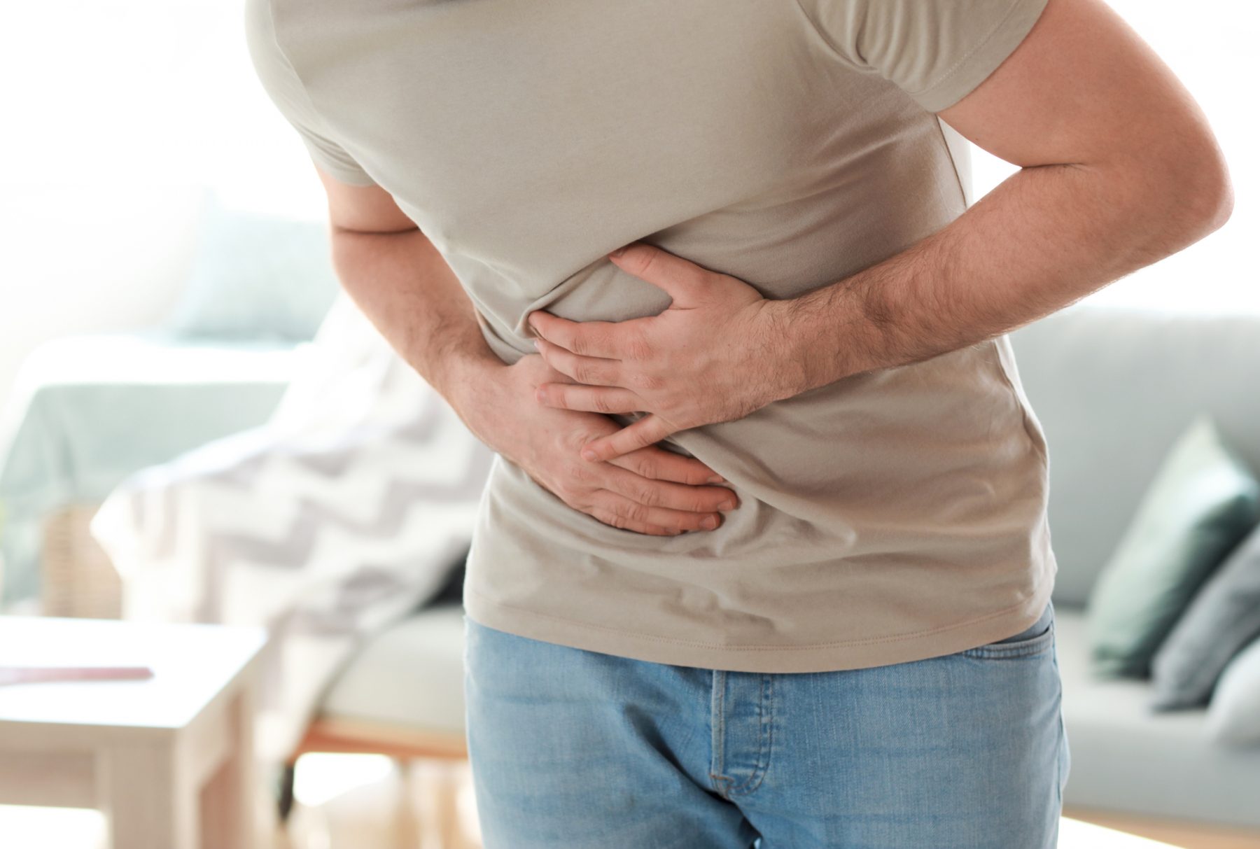 Man bent over with digestive pain at home