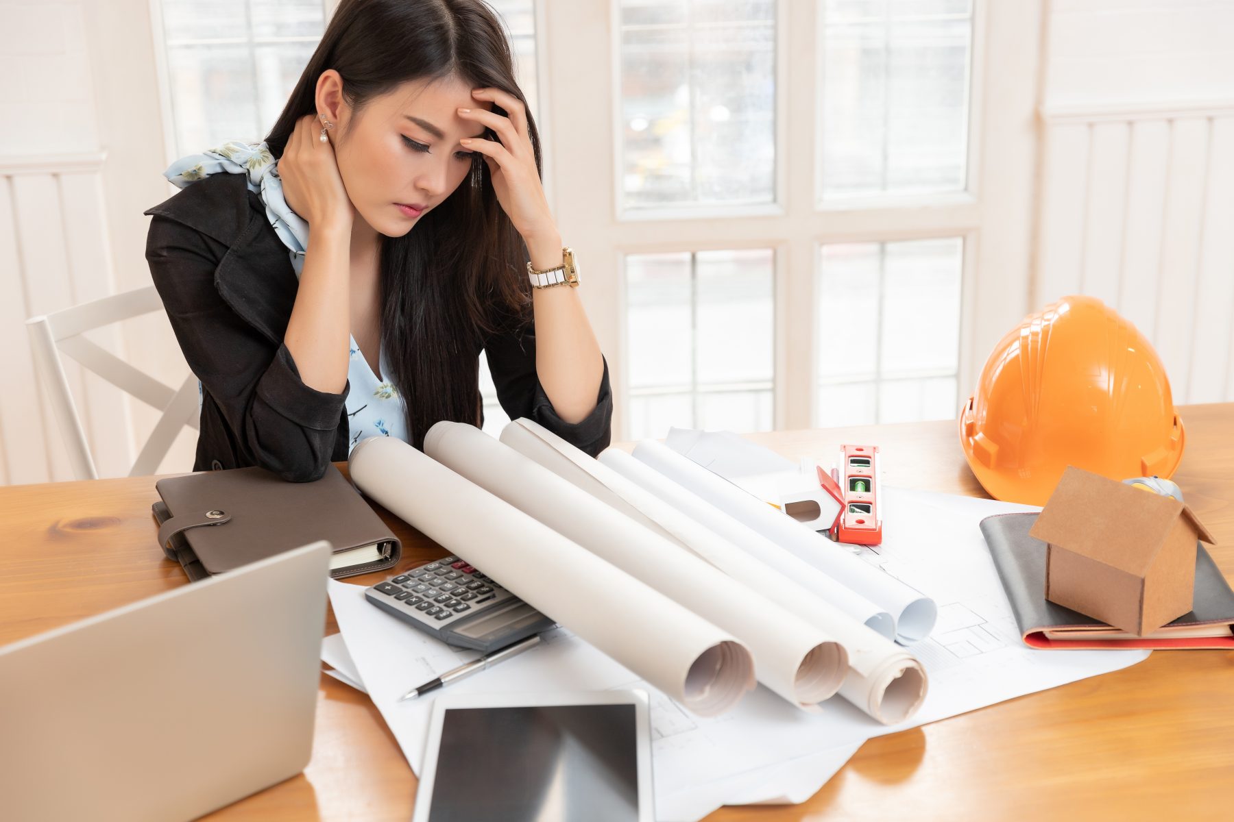 Woman in office with building drawings feeling sick