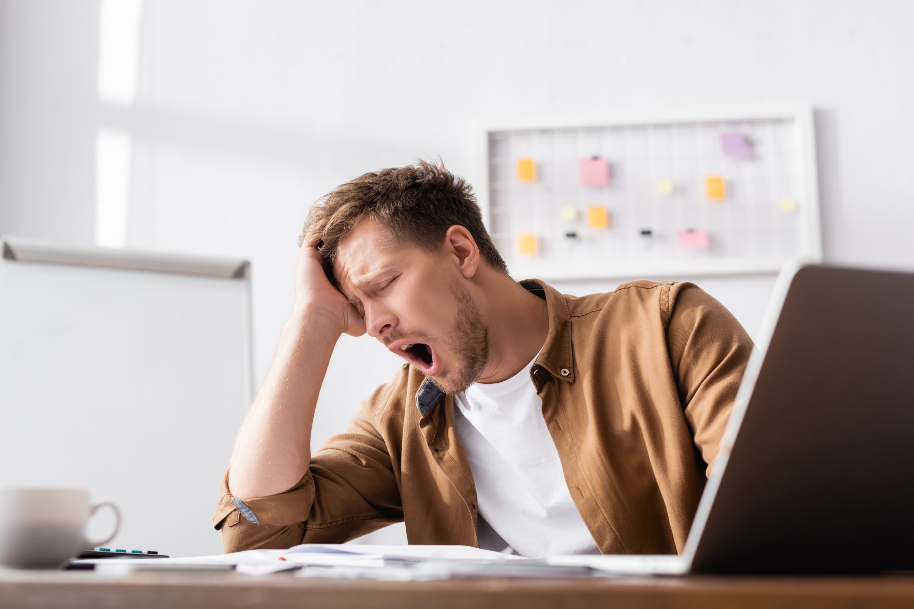 Man yawning with fatigue in office
