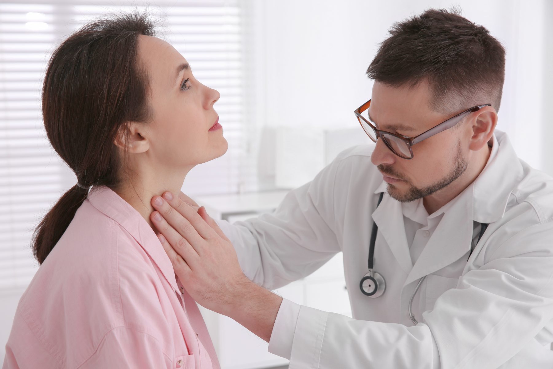 Doctor investigating hypothyroidism by examining thyroid gland of patient
