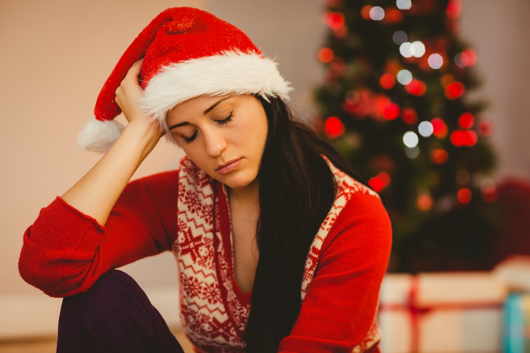 Woman with Seasonal Affective Disorder wearing holiday garb with Christmas tree in background