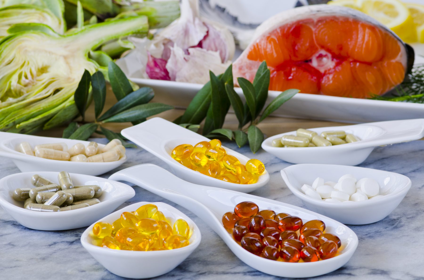 Bowls of nutritional supplements with healthy foods in background