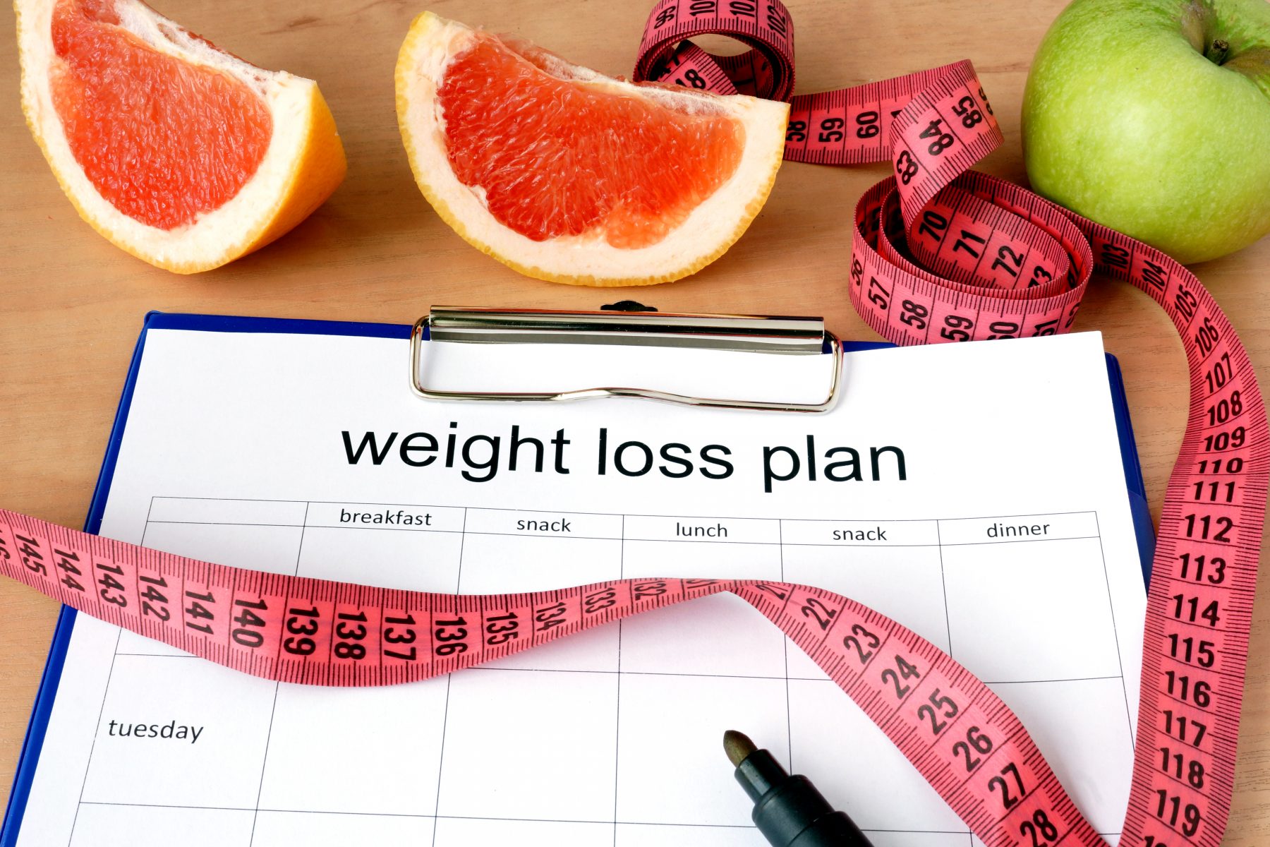 Weight loss plan calendar with fruit and measuring tape
