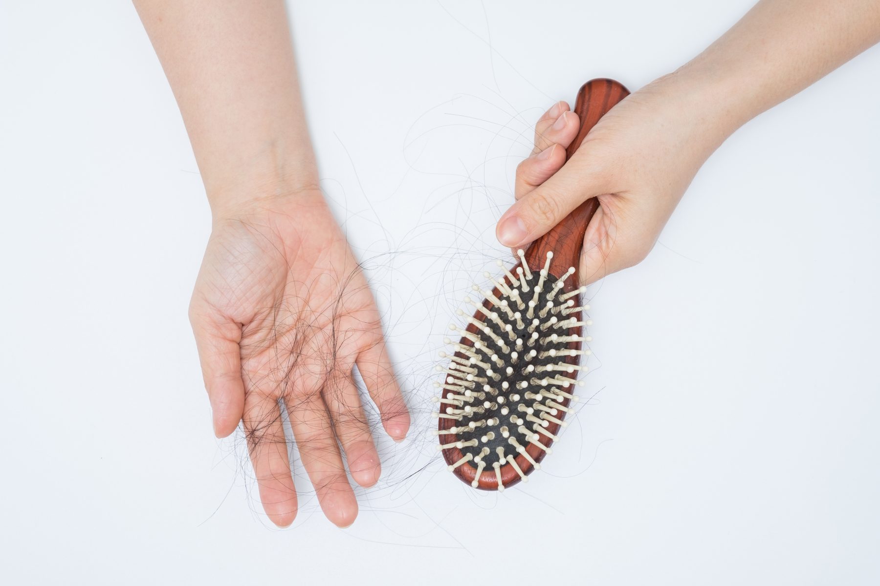 Person pulling hair out of hair brush from hair loss