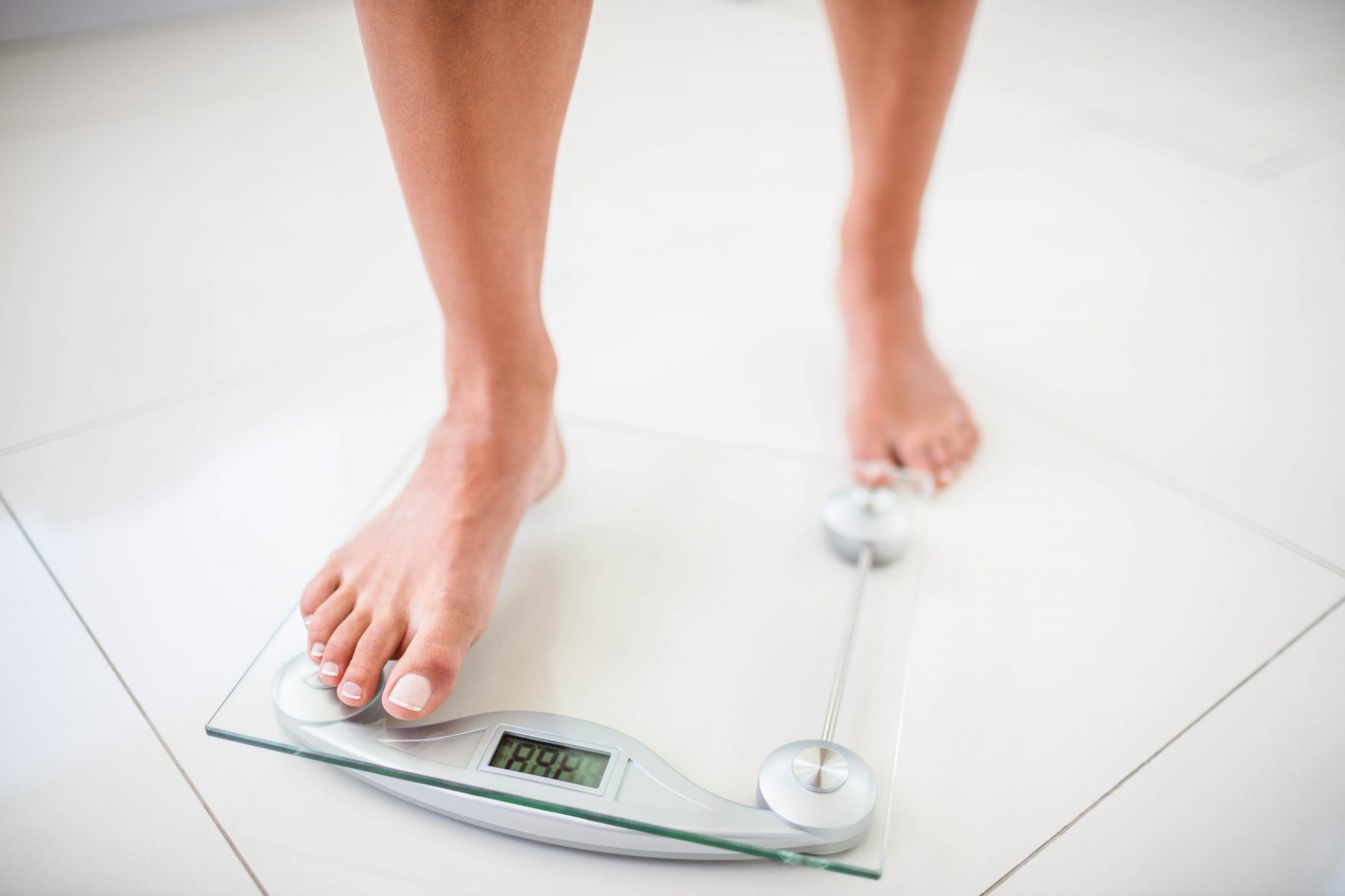 Womans feet going on weighting scale at home