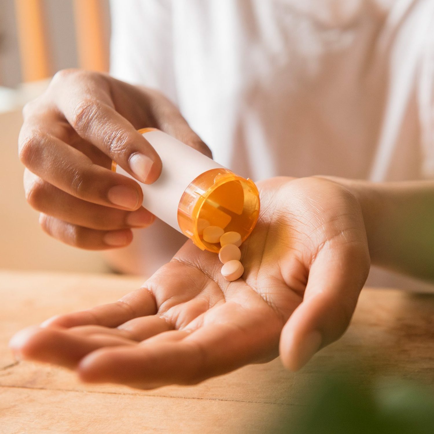Elderly woman spilling antibiotics into her hand from a pill bottle