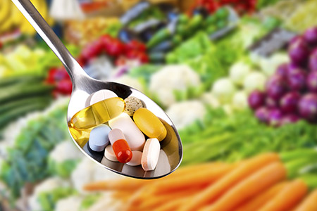 Nutritional supplements in a spoon with vegetables in the background