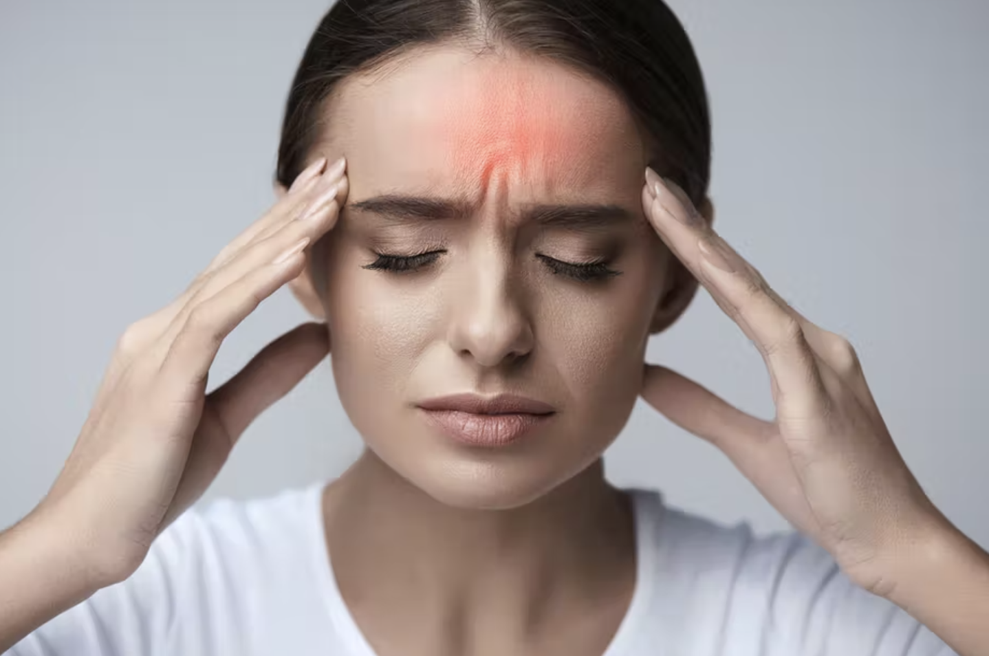 Woman with headache clutching her temples with red overlay