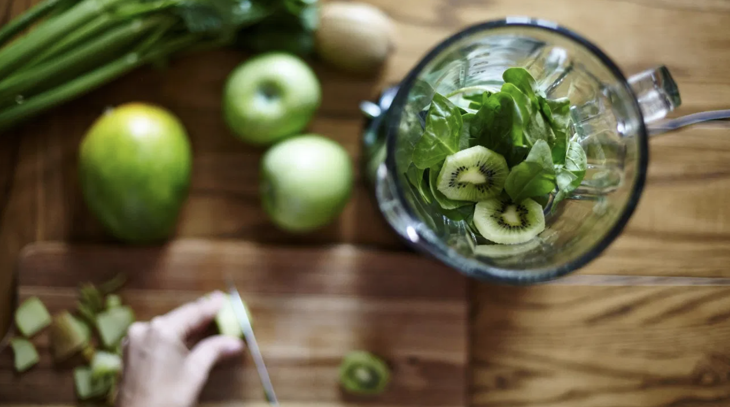 Person preparing a green detox shake in a blender