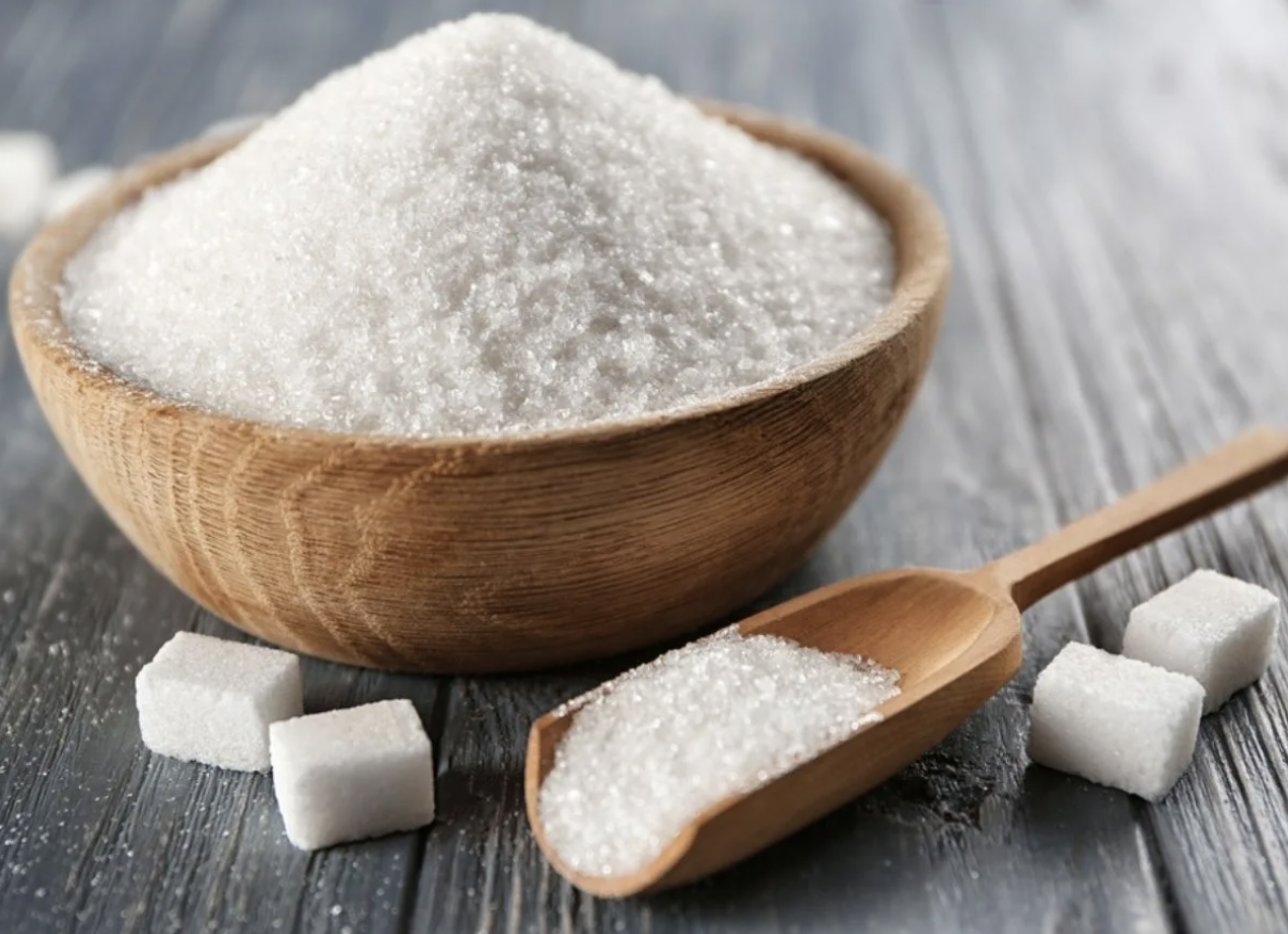 Heaping bowl of sugar with scoop and sugar cubes