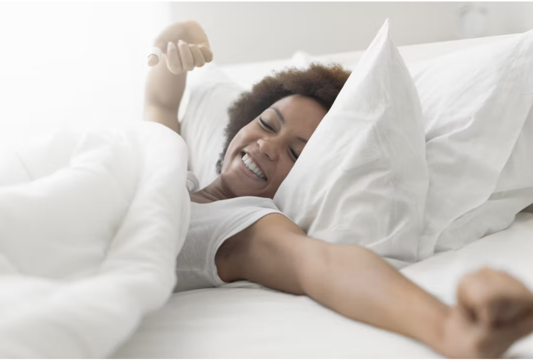 Woman awaking in bed feeling happy and refreshed