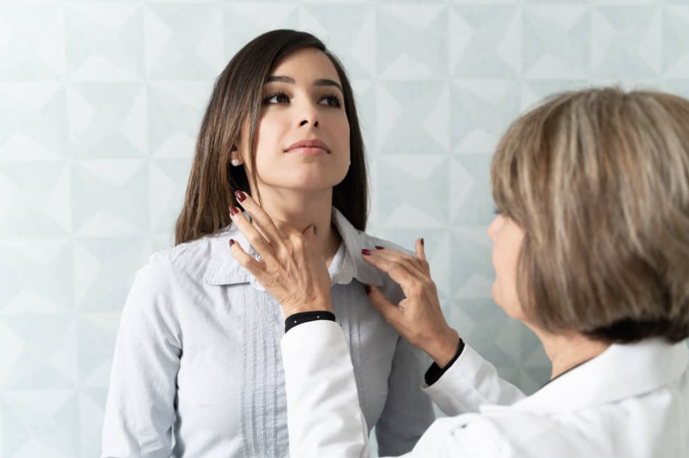 Doctor checking woman's thyroid