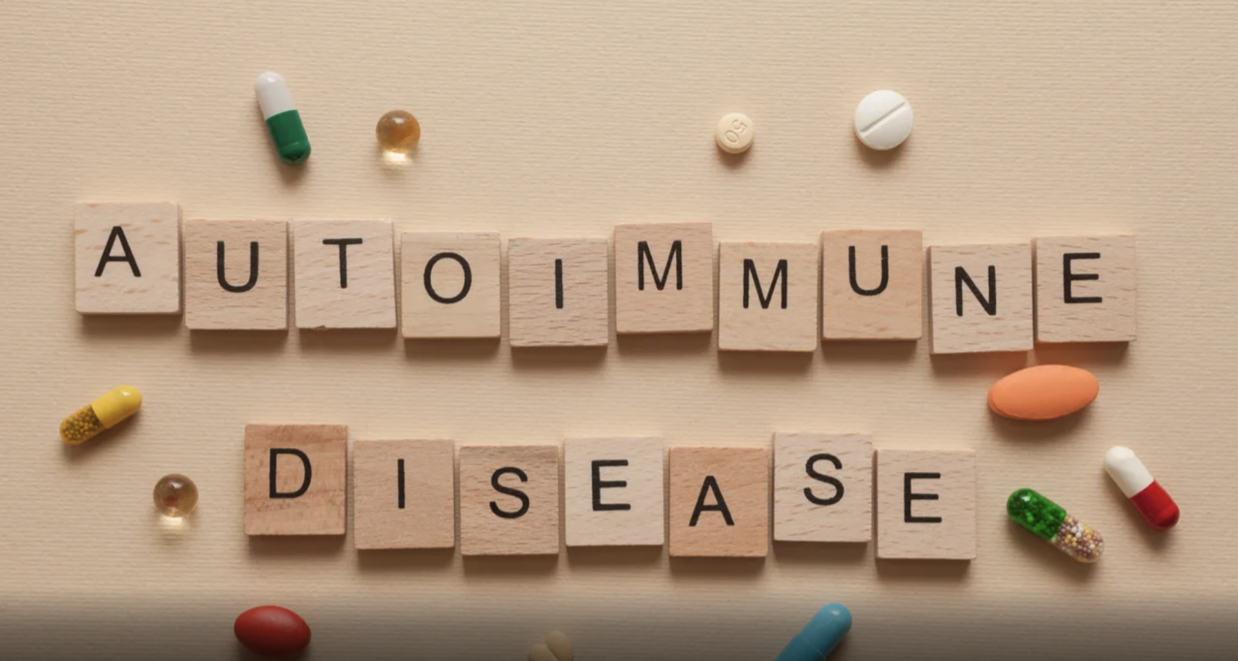 Autoimmune disease spelled out on wooden tiles surrounded be pills