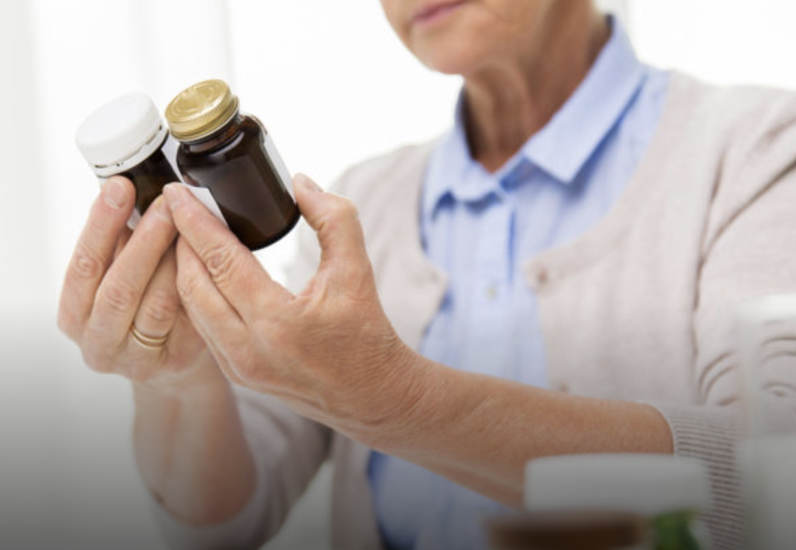 Elderly woman checking the labels of two different multivitamins