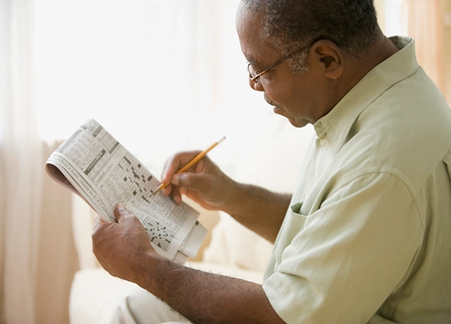 Elderly man doing crossword puzzle