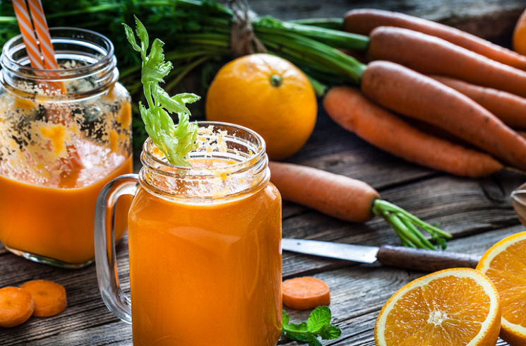 Detoxifying smoothies in glass jars surrounded by healthy fruits and vegetables