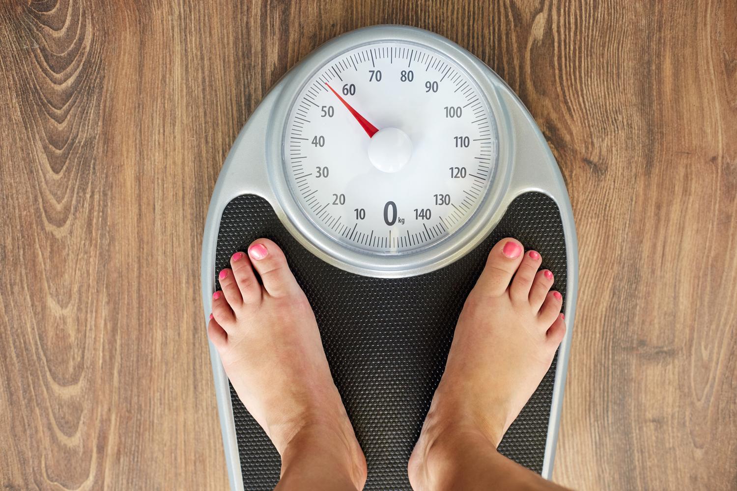 Woman checking her weight on a scale