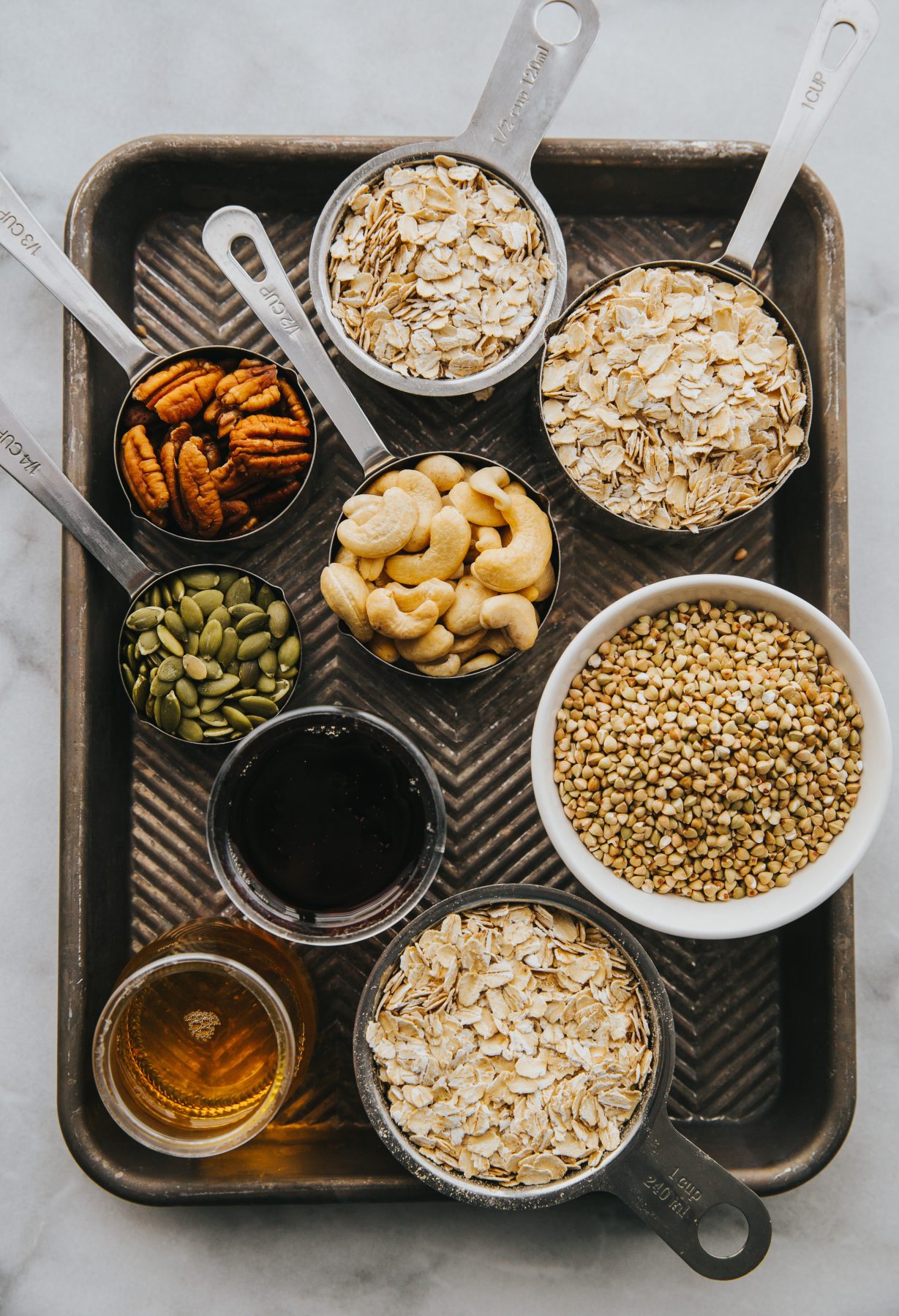 Nuts and seeds in bowls and measuring cups on a tray