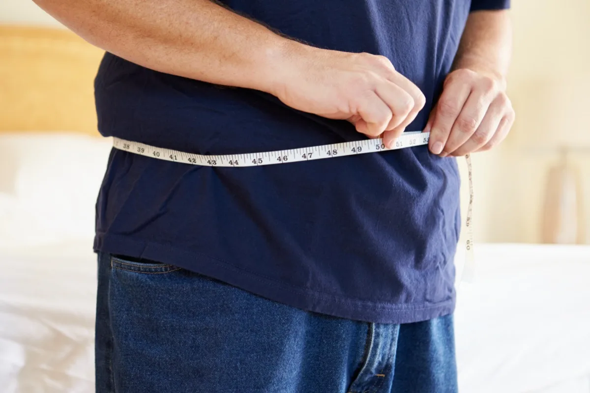 Man checking weight and waist size with measuring tape