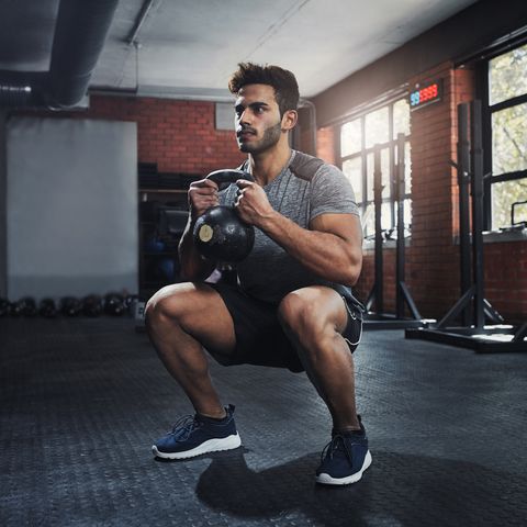 Man doing leg workouts in a gym with kettle weights