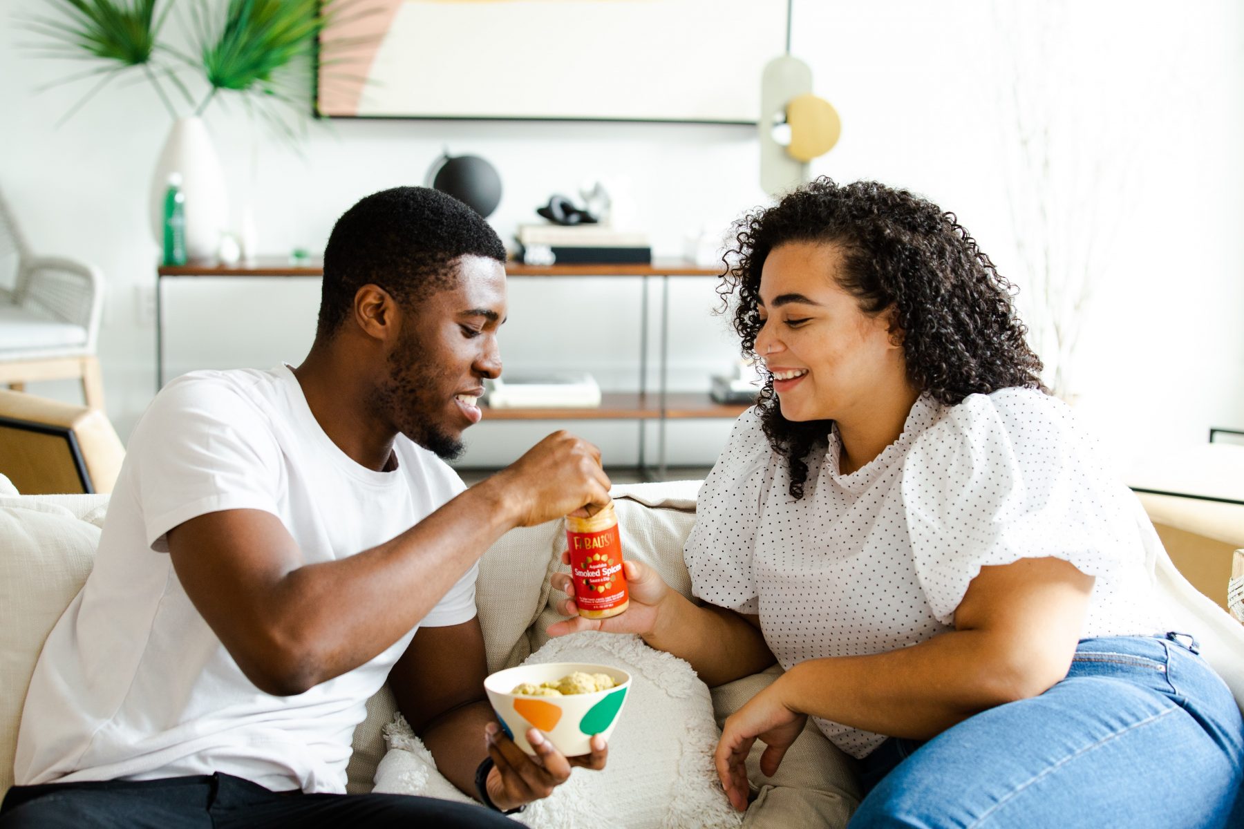 Couple eating unhealthy food together on a sofa