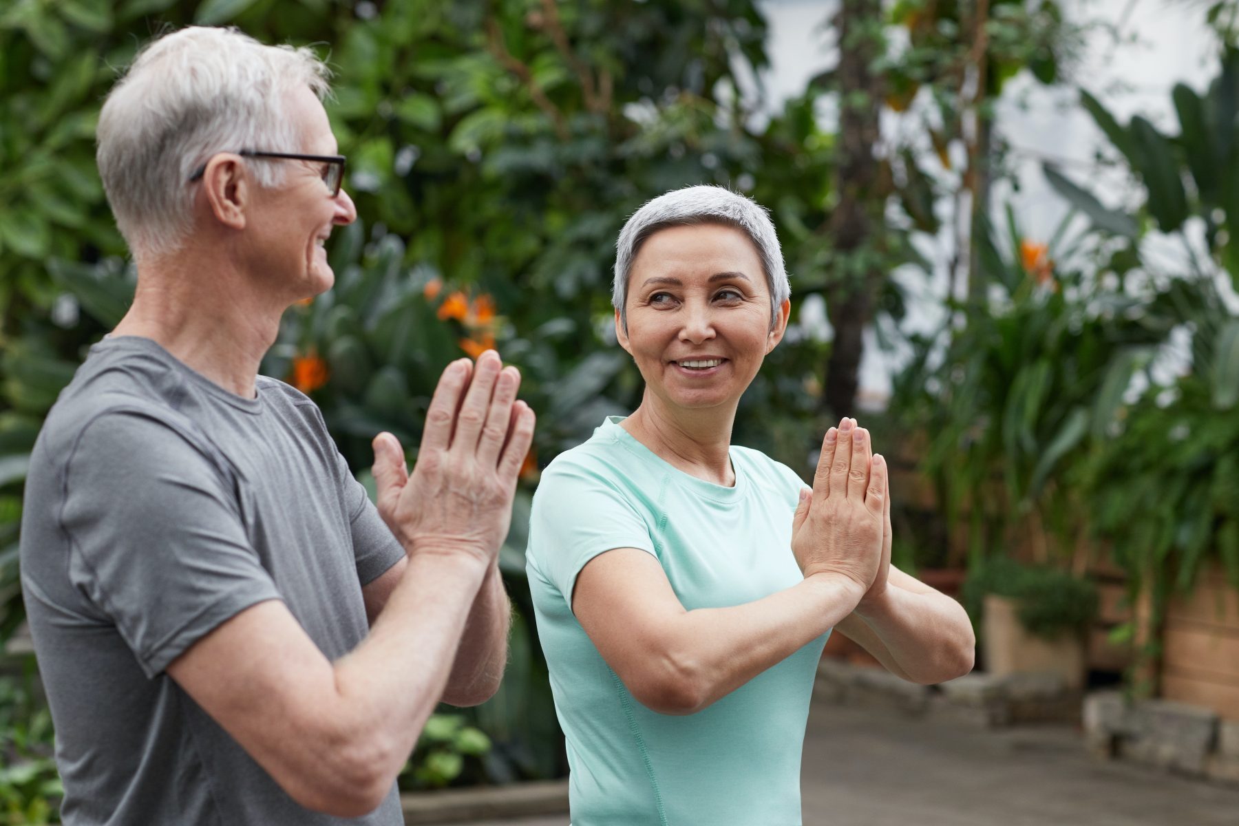 Healthy and happy older couple meditating together in a tropical garden