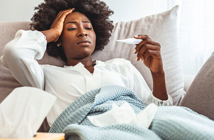 Woman with flu in bed checking her temperature