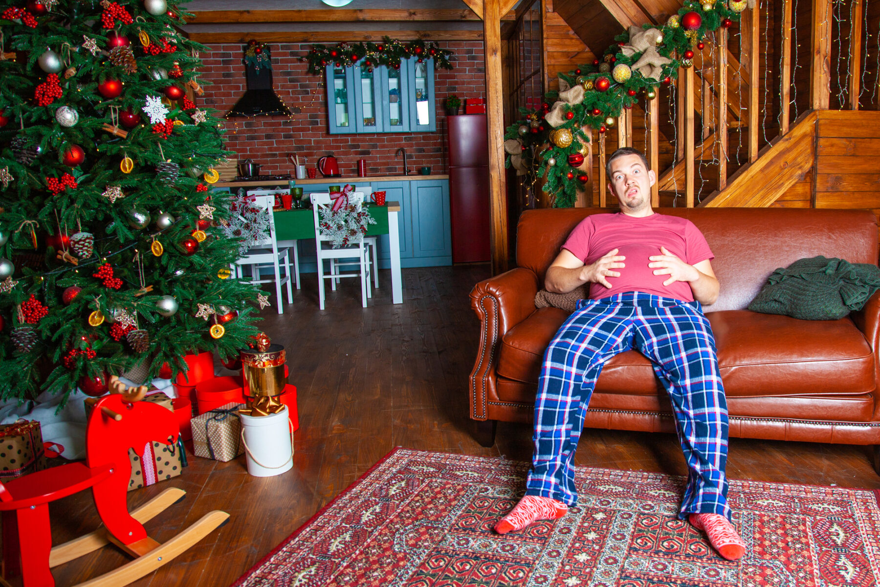 Man holding his stomach next to a Christmas tree