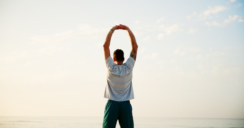 Man stretching his arms overhead at sunrise, representing holistic wellness and integrative medicine in Atlanta.
